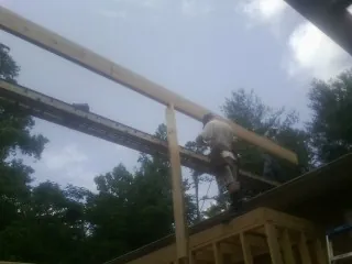 Carpenter setting a ridge beam over a new addition frame — Ice Dam Removal by Roofing Brothers in Somerville